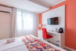 een slaapkamer met een bed en een bureau met een rode stoel bij THE Hotel MASA Almirante LISBON Stylish in Lissabon +10 foto's