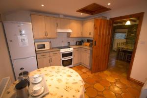 a kitchen with a white refrigerator and a table at Holmws Holiday Cottages in Newport Pembrokeshire