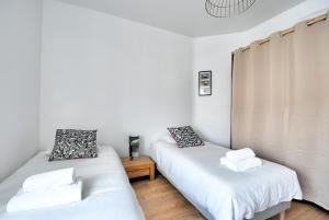 Dos camas en una habitación con paredes blancas. en La Traversée Brestoise - Appartement tout confort avec parking privatif au centre-ville, en Brest