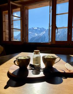 a table with two bowls on a table with a view at Heimelige Wohnung in einem Walliser Haus in Staldenried