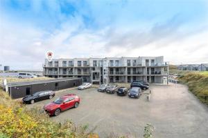 ein Parkplatz mit vor einem Gebäude geparkten Autos in der Unterkunft 824 Hvide Sande - Mamrelund 6 2. A in Hvide Sande