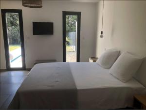 a bedroom with a large white bed with two windows at La Casa Fabrielo in Graveson