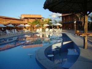 a swimming pool with chairs and umbrellas at a resort at Chalé em Barreirinhas in Barreirinhas