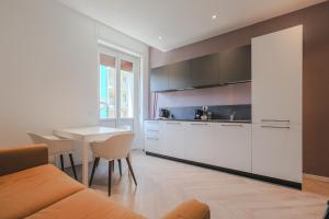 a kitchen with white cabinets and a table with chairs at DomoHouse in Domodossola
