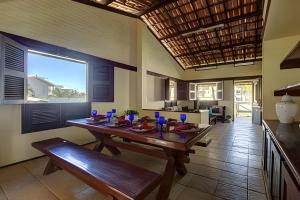 a dining room with a wooden table and a bench at Linda no BEACH PARK-16 pessoas - HOUSINGCEARÁ in Berra Bode