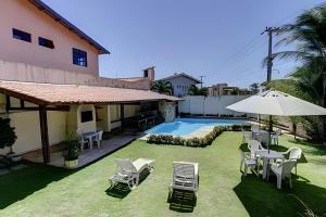 a yard with chairs and an umbrella and a pool at Linda no BEACH PARK-16 pessoas - HOUSINGCEARÁ in Berra Bode