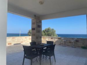 a table and chairs on a patio with a view of the ocean at SeaSummerSand Apartment in Chios