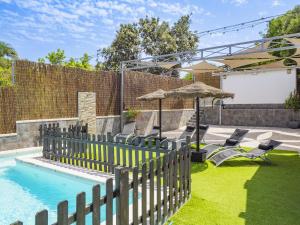 a fence next to a pool with chairs and an umbrella at Cubo's Casa Rural Maylu in Villafranco de Guadalhorce