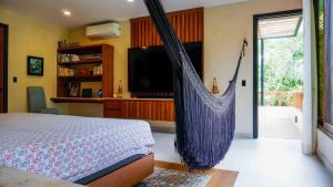 1 dormitorio con 1 cama, TV y hamaca en Spacious and luxurious villa with 4 bedrooms, swimming pool, tennis court, and beach within walking distance, en Playa del Carmen