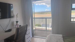 a bedroom with a bed and a balcony with a view at Witsand Holiday House in Witsand
