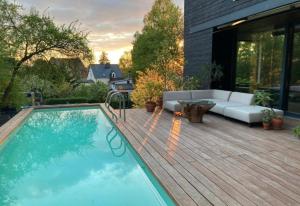 a swimming pool on a wooden deck with a couch and a couch at Poolvilla in Caputh