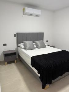 a bedroom with a large bed with a black blanket at Hotel De León Estadio in Medellín