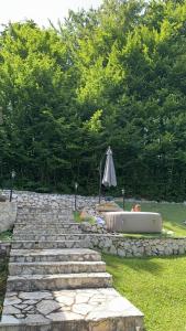a stone path with an umbrella next to a bathtub at Forest Escape Banja Luka in Banja Luka +5 photos