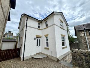 a white house with a white door and a fence at Rawes Cottage Kendal in Kendal
