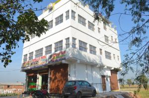 a white building with a car parked in front of it at Family Hotel Stay In Hotel AV Priya Rajgir in Rājgīr