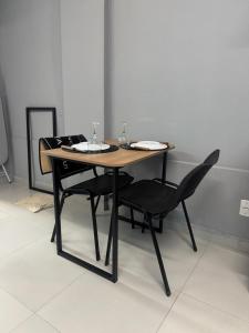 a wooden table with two chairs and a table with two plates at Liv Stay in Brasília