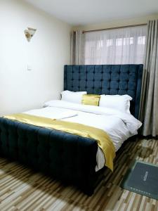 a large bed with a blue headboard in a room at Kitengela two bedroom stays in Kitengela 