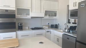 a kitchen with white cabinets and a counter top at Witsand Holiday House in Witsand +20 photos