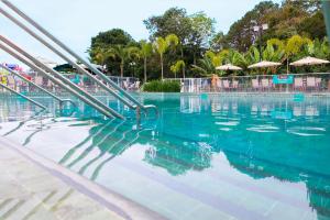 a swimming pool with blue water and some umbrellas at Hotel Vilage Inn All Inclusive Poços de Caldas By Nacional Inn in Poços de Caldas