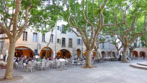 a group of people sitting at tables in a courtyard with trees at Charming small house close to Uzès in Foissac