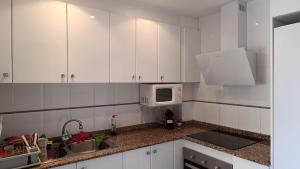 a white kitchen with a sink and a microwave at Arc Blau in Piles