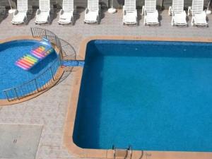 a blue swimming pool next to a row of chairs at Hotel Amigos in Obzor