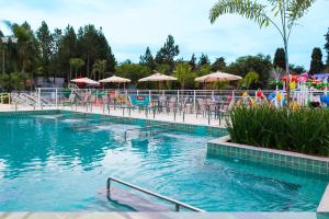 a swimming pool with tables and chairs and umbrellas at Hotel Vilage Inn All Inclusive Poços de Caldas By Nacional Inn in Poços de Caldas