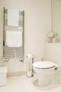 a white bathroom with a toilet and towels at Stockley Apartments in West Drayton +30 photos