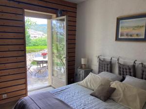 a bedroom with a bed and a sliding glass door at Le Mas de la Roche in Montbrison-sur-Lez