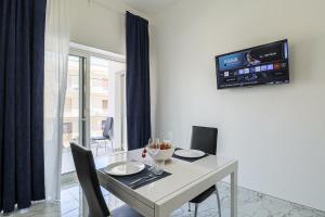 a dining room table with chairs and a tv on a wall at Nettuno80 3 by Casa di Marco AP33 in Lido Conchiglie