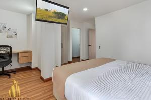 a bedroom with a bed and a tv on the wall at Aria Living 200 - Vibrant Apartment in Laureles in Guayaquil