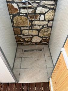 a shower in a room with a stone wall at Himara Hostel in Himare