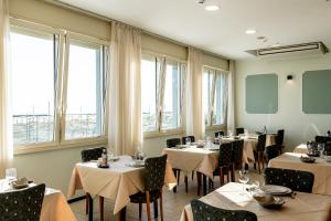 a dining room with tables and chairs and windows at Hotel Acquamarina Viserba in Rimini