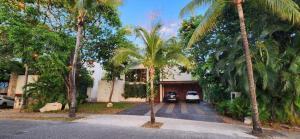 una casa con palmeras delante en Spacious and luxurious villa with 4 bedrooms, swimming pool, tennis court, and beach within walking distance, en Playa del Carmen