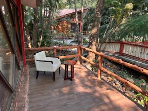 a wooden deck with a chair and a table on it at Aayush Resort Karjat in Kālundri