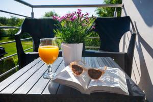 a glass of orange juice and sunglasses on a table with a book at Apartament Perfect House Morski 8 in Władysławowo +11 photos