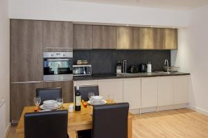 a kitchen with a wooden table with chairs and a counter at Stockley Apartments in West Drayton
