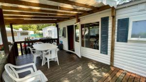 a porch with a table and chairs on a house at Mobile home in a family campsite 3 km from the beaches in Les Mathes