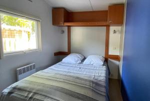 a small bedroom with a bed and a window at Mobile home in a family campsite 3 km from the beaches in Les Mathes +14 photos