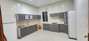 a large kitchen with gray cabinets and a sink at فيلا بحوش خاص in Al Baha