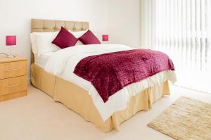 a bedroom with a large bed with a purple blanket at Stockley Apartments in West Drayton