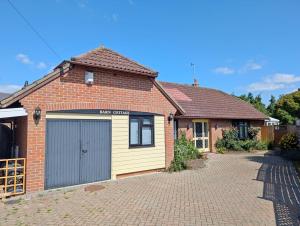 a brick house with a garage on a driveway at Barn Cottage in Wick