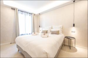 ein Schlafzimmer mit einem großen weißen Bett mit einem großen Fenster in der Unterkunft Hôtel particulier Marceau - Centre - Neuf - Suites de 3 à 28 chambres in Cannes