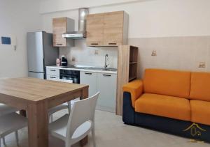 a kitchen with a table and an orange couch in a kitchen at Maia Etna Sea Guest House in Riposto