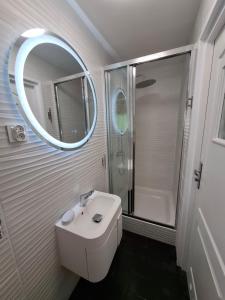 a white bathroom with a sink and a mirror at Apartamenty Młyn in Męcikał