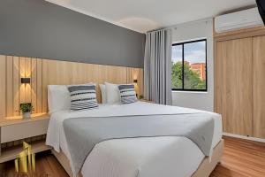una camera da letto con un grande letto bianco e una finestra di Aria Living 401 - Sophisticated Living in Laureles a Guayaquil