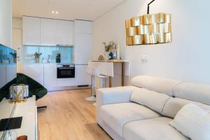a living room with a white couch and a kitchen at Studio w/ Balcony, Pool & Gym | Antas by Host Wise in Porto