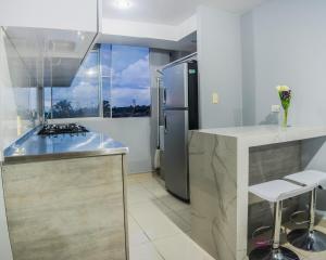 a kitchen with a stainless steel refrigerator and a counter at Apartamento con parqueadero, piscinas y wifi a 5 min del parque del café in Montenegro +15 photos