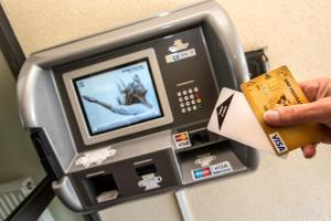 une personne introduisant une carte de crédit dans une machine à atm dans l'établissement Hotel Eco - A75, à Banassac