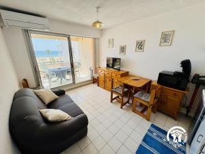 un soggiorno con un divano, un tavolo e una televisione di Le grand bleu a Narbonne